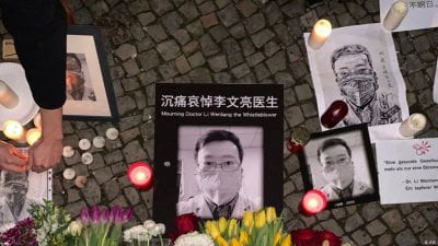 Candles and flowers are placed beside photo of doctor Li Wenliang