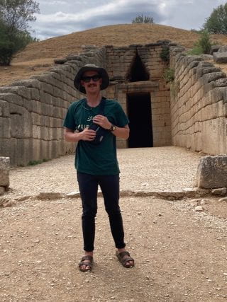 Author in front of a monumental Mycenaean tholos tomb from the Bronze Age in modern-day Argolis, Greece