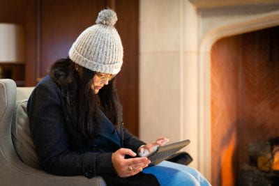 A student on an ipad sitting beside the fireplace