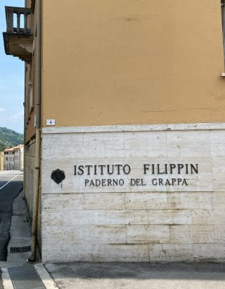 Photo of the side of yellow building. The sign on it reads" Instituto Flippin Paderno del Grappa"