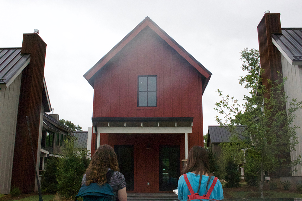 Two female students sketch a gabled barn red house. 