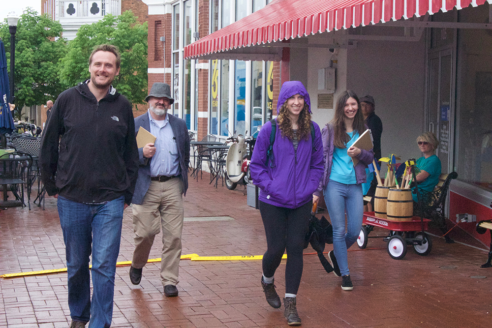 Students, professor and architect stroll in rainy downtown.