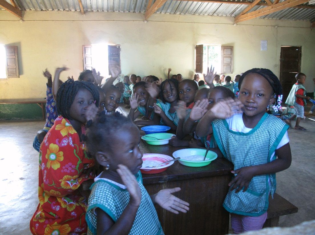 A group of school children are gathered around a table for a meal. 